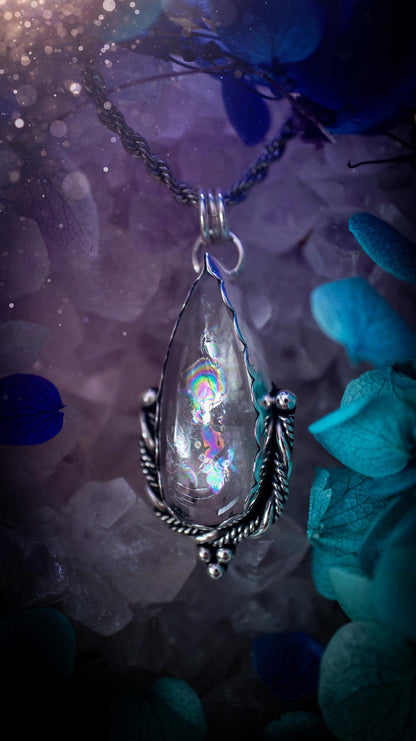 Handmade white topaz pendant necklace crafted from fine silver and sterling silver. The teardrop white topaz gemstone displays stunning natural cluster rainbows and subtle sparkle within the stone. The elegant silver setting highlights the crystal's unique inclusions and clarity. Photographed against a neutral background, this artisan gemstone necklace makes a thoughtful November birthstone gift. A necklace that is the definition of celestial and fairycore!