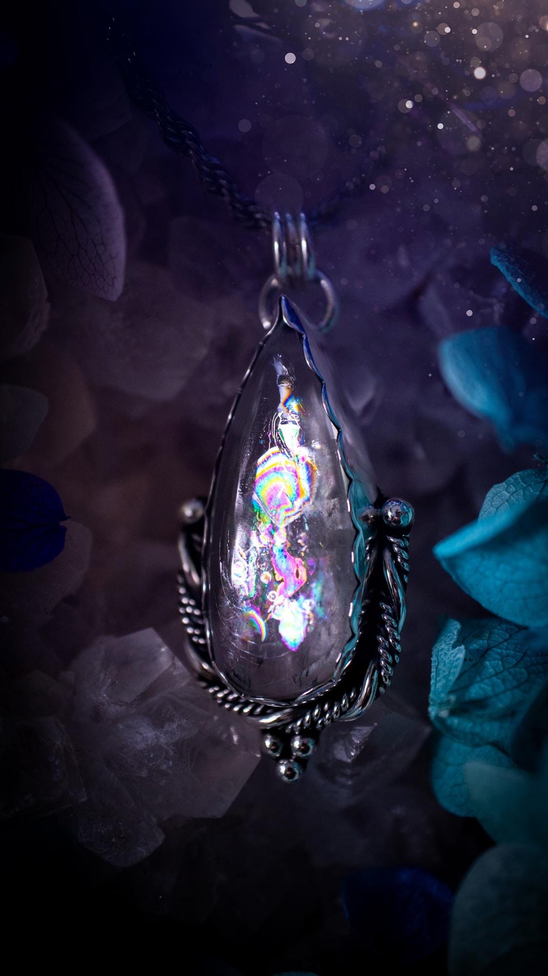 Handmade white topaz pendant necklace crafted from fine silver and sterling silver. The teardrop white topaz gemstone displays stunning natural cluster rainbows and subtle sparkle within the stone. The elegant silver setting highlights the crystal's unique inclusions and clarity. Photographed against a neutral background, this artisan gemstone necklace makes a thoughtful November birthstone gift. A necklace that is the definition of celestial and fairycore!