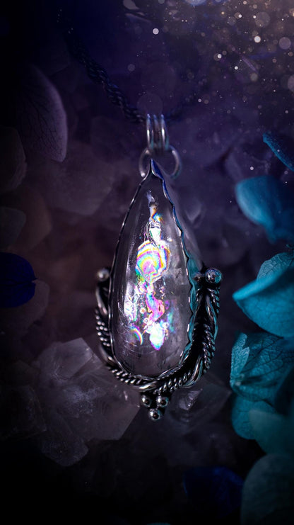 Handmade white topaz pendant necklace crafted from fine silver and sterling silver. The teardrop white topaz gemstone displays stunning natural cluster rainbows and subtle sparkle within the stone. The elegant silver setting highlights the crystal's unique inclusions and clarity. Photographed against a neutral background, this artisan gemstone necklace makes a thoughtful November birthstone gift. A necklace that is the definition of celestial and fairycore!