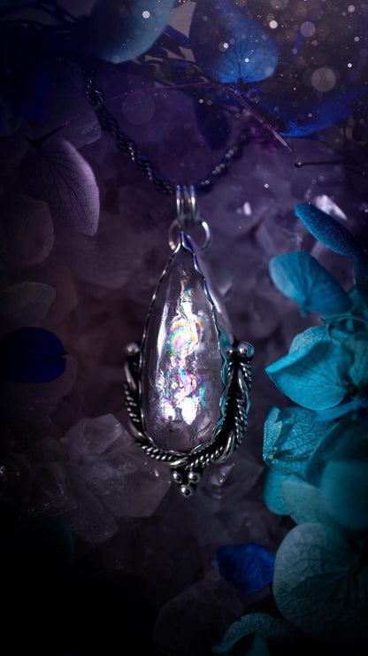 Handmade white topaz pendant necklace crafted from fine silver and sterling silver. The teardrop white topaz gemstone displays stunning natural cluster rainbows and subtle sparkle within the stone. The elegant silver setting highlights the crystal's unique inclusions and clarity. Photographed against a neutral background, this artisan gemstone necklace makes a thoughtful November birthstone gift. A necklace that is the definition of celestial and fairycore!