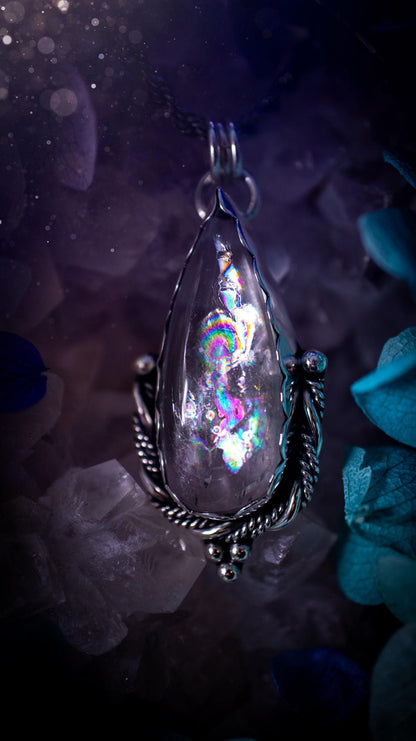 Handmade white topaz pendant necklace crafted from fine silver and sterling silver. The teardrop white topaz gemstone displays stunning natural cluster rainbows and subtle sparkle within the stone. The elegant silver setting highlights the crystal's unique inclusions and clarity. Photographed against a neutral background, this artisan gemstone necklace makes a thoughtful November birthstone gift. A necklace that is the definition of celestial and fairycore!