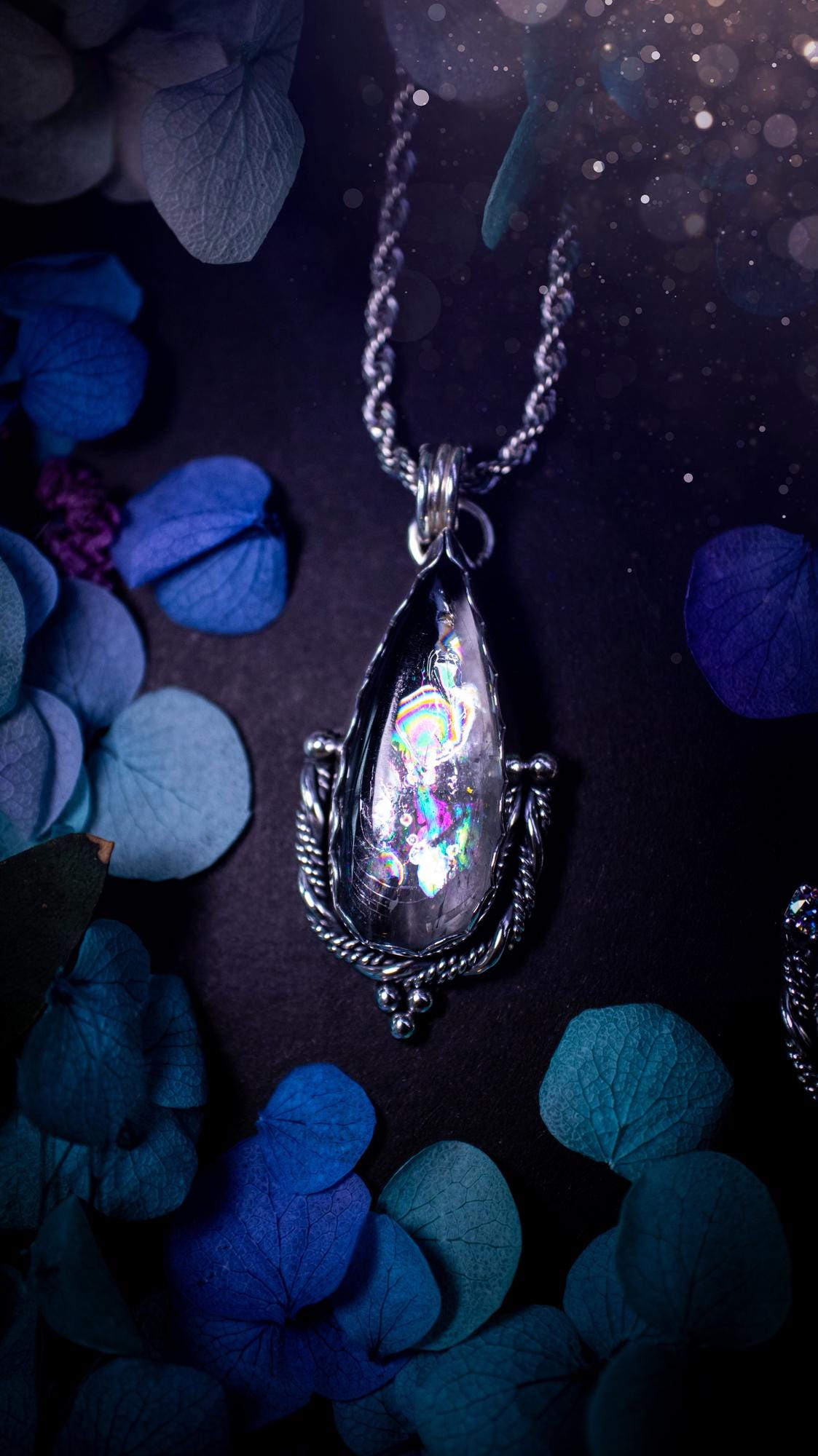 Handmade white topaz pendant necklace crafted from fine silver and sterling silver. The teardrop white topaz gemstone displays stunning natural cluster rainbows and subtle sparkle within the stone. The elegant silver setting highlights the crystal's unique inclusions and clarity. Photographed against a neutral background, this artisan gemstone necklace makes a thoughtful November birthstone gift. A necklace that is the definition of celestial and fairycore!