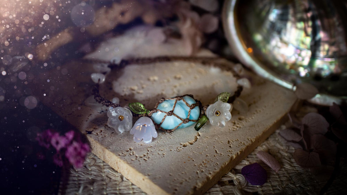 Beautifully handmade, authentic and natural crystal larimar, macrame fairy bracelet. This bracelet has been made using high quality Linhasita waxed cord in cedar brown colour. Featuring a beautiful larimar crystal as the focal point that is surrounded by glass flowers that have 24k plated gold beads, moonstone chip crystals and little cute leaves. The bracelet also has a slider knot for size adjustments. Ideal for anyone who loves a whimsical aesthetic, crystals, florals and hippy jewellery.