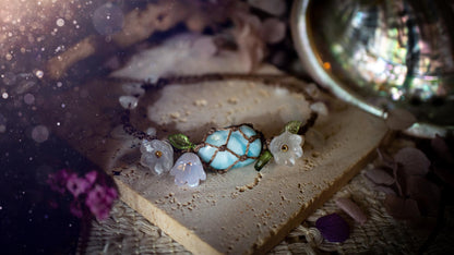 Beautifully handmade, authentic and natural crystal larimar, macrame fairy bracelet. This bracelet has been made using high quality Linhasita waxed cord in cedar brown colour. Featuring a beautiful larimar crystal as the focal point that is surrounded by glass flowers that have 24k plated gold beads, moonstone chip crystals and little cute leaves. The bracelet also has a slider knot for size adjustments. Ideal for anyone who loves a whimsical aesthetic, crystals, florals and hippy jewellery.