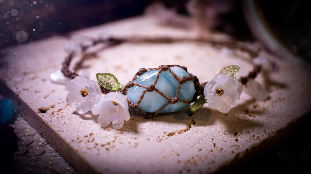 Beautifully handmade, authentic and natural crystal larimar, macrame fairy bracelet. This bracelet has been made using high quality Linhasita waxed cord in cedar brown colour. Featuring a beautiful larimar crystal as the focal point that is surrounded by glass flowers that have 24k plated gold beads, moonstone chip crystals and little cute leaves. The bracelet also has a slider knot for size adjustments. Ideal for anyone who loves a whimsical aesthetic, crystals, florals and hippy jewellery.