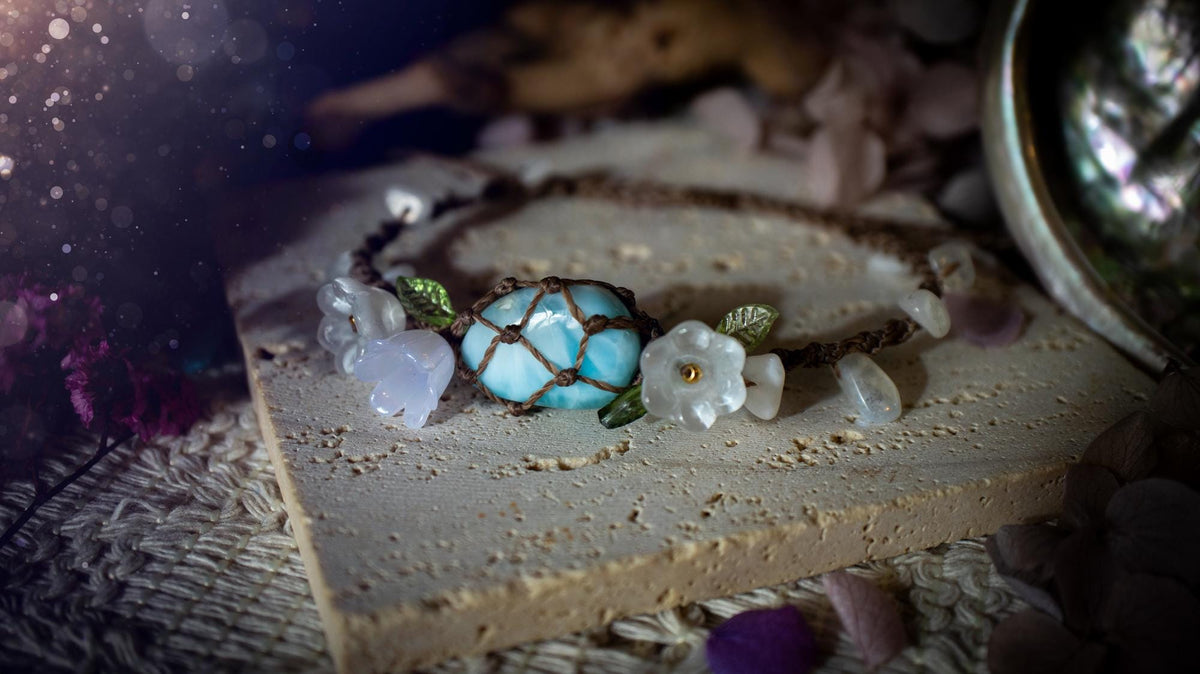 Beautifully handmade, authentic and natural crystal larimar, macrame fairy bracelet. This bracelet has been made using high quality Linhasita waxed cord in cedar brown colour. Featuring a beautiful larimar crystal as the focal point that is surrounded by glass flowers that have 24k plated gold beads, moonstone chip crystals and little cute leaves. The bracelet also has a slider knot for size adjustments. Ideal for anyone who loves a whimsical aesthetic, crystals, florals and hippy jewellery.