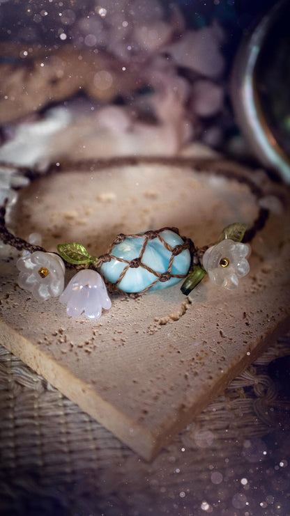 Beautifully handmade, authentic and natural crystal larimar, macrame fairy bracelet. This bracelet has been made using high quality Linhasita waxed cord in cedar brown colour. Featuring a beautiful larimar crystal as the focal point that is surrounded by glass flowers that have 24k plated gold beads, moonstone chip crystals and little cute leaves. The bracelet also has a slider knot for size adjustments. Ideal for anyone who loves a whimsical aesthetic, crystals, florals and hippy jewellery.