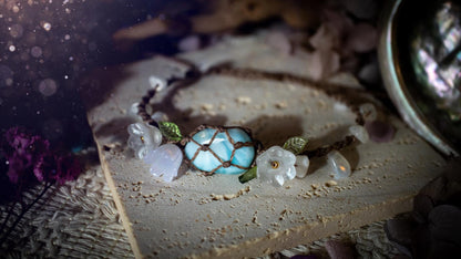 Beautifully handmade, authentic and natural crystal larimar, macrame fairy bracelet. This bracelet has been made using high quality Linhasita waxed cord in cedar brown colour. Featuring a beautiful larimar crystal as the focal point that is surrounded by glass flowers that have 24k plated gold beads, moonstone chip crystals and little cute leaves. The bracelet also has a slider knot for size adjustments. Ideal for anyone who loves a whimsical aesthetic, crystals, florals and hippy jewellery.